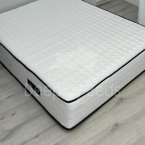 White mattress with quilted pattern on a wooden floor, brand 'Deep Sleeps' visible.