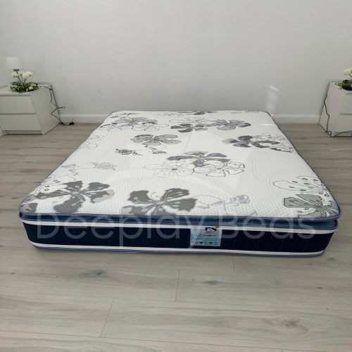 Floral-patterned mattress on a wooden floor with white walls.