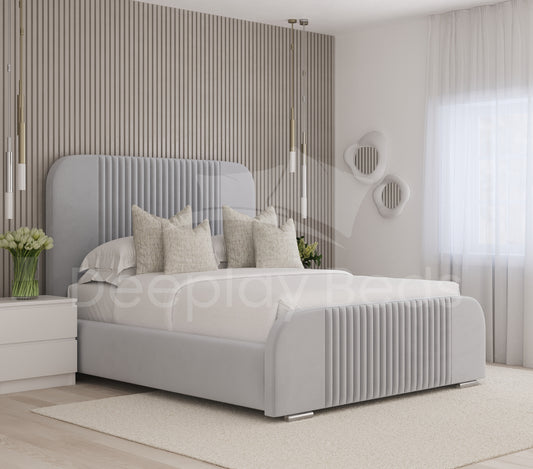 Manchester Silver Upholstered Ottoman Storage Bed with curved high headboard, stylish pleated design, and spacious storage compartment for a modern, luxurious bedroom.