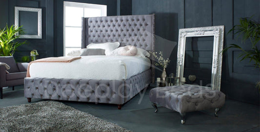 Suffolk Chesterfield Wingback High Headboard Ottoman Storage Bed Frame in grey, featuring luxurious tufted fabric, a high wingback design, and hidden storage space beneath the bed.