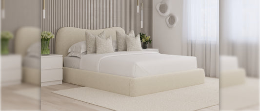 Cream upholstered king size ottoman storage bed with curved headboard, styled with neutral cushions in a modern bedroom with slatted wall panels and soft natural light
