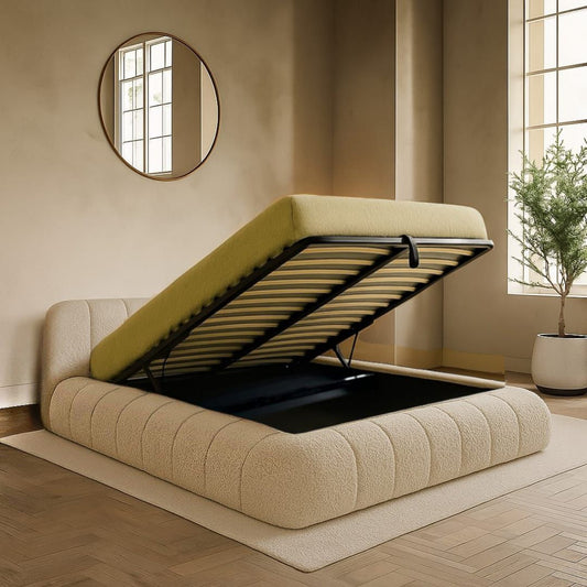 Beige upholstered bed with raised headboard in a room with a mirror and plant.
