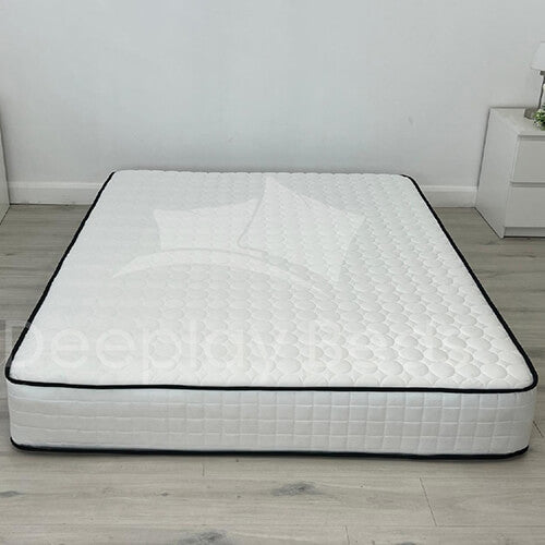 White mattress with black border on a wooden floor