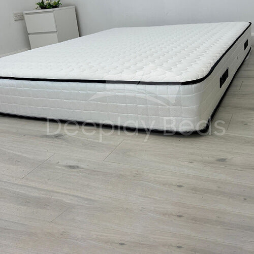 White mattress on a wooden floor with 'Deeplyy Beds' branding.
