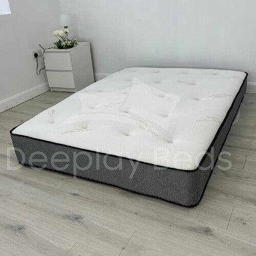 Gray and white mattress on a wooden floor with 'Deepplay Beds' branding.