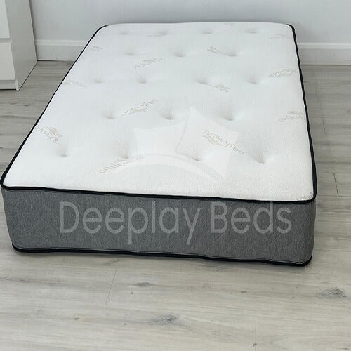 Gray and white mattress with 'Deeplay Beds' branding on a wooden floor.