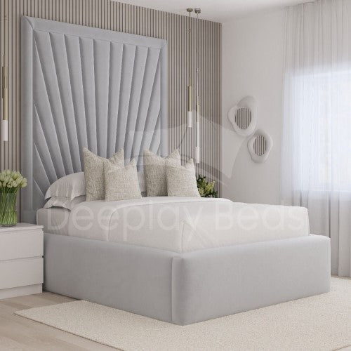 Modern bedroom with a gray upholstered bed and decorative headboard.